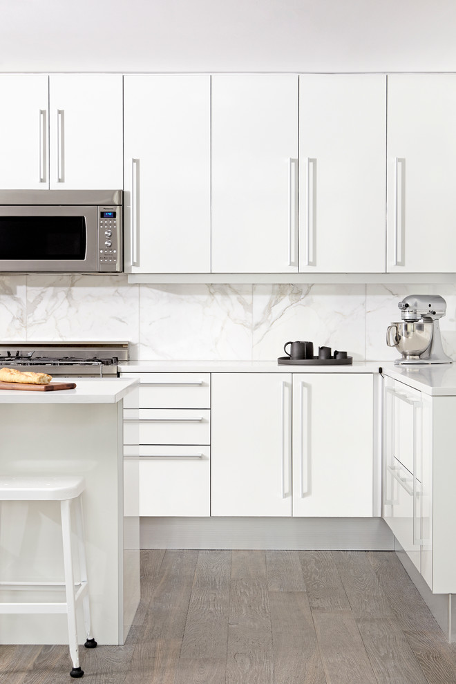 Photo of a contemporary kitchen in Toronto with flat-panel cabinets, white cabinets, white splashback, stainless steel appliances, medium hardwood floors and with island.