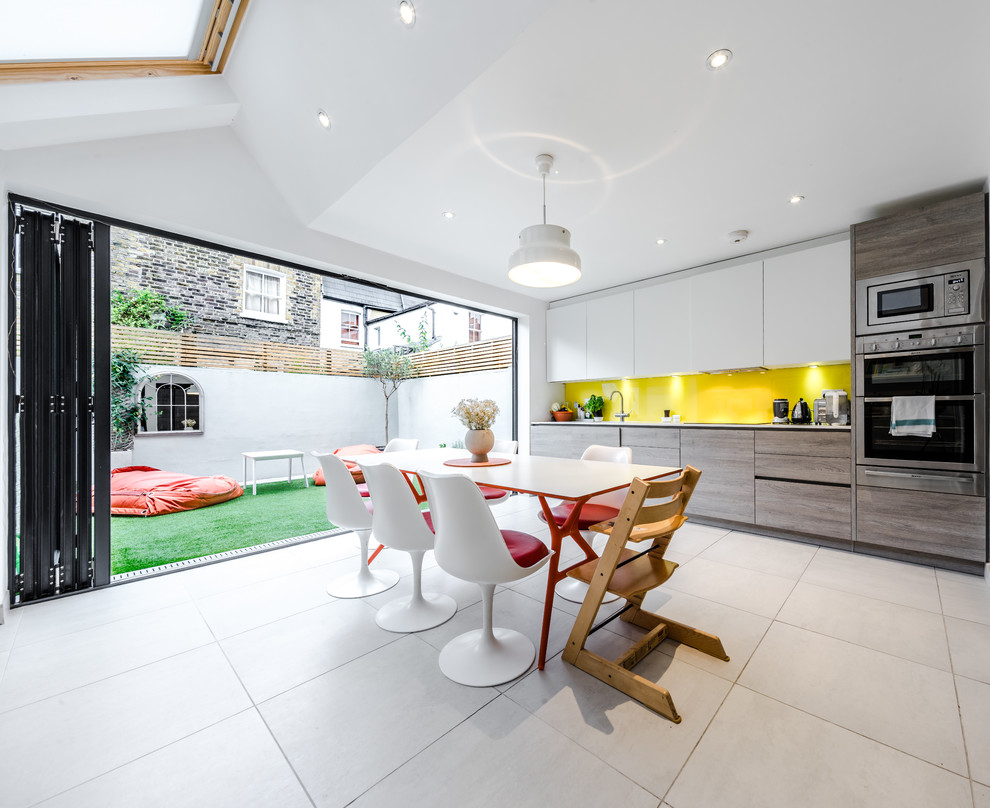 Inspiration for a contemporary single-wall eat-in kitchen in London with flat-panel cabinets, white cabinets, yellow splashback, stainless steel appliances and no island.