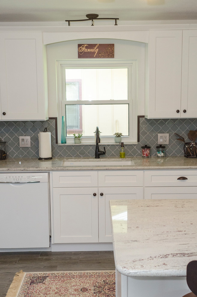 Photo of a large transitional l-shaped eat-in kitchen in Orlando with an undermount sink, shaker cabinets, white cabinets, granite benchtops, multi-coloured splashback, glass sheet splashback, white appliances, porcelain floors, with island and grey floor.