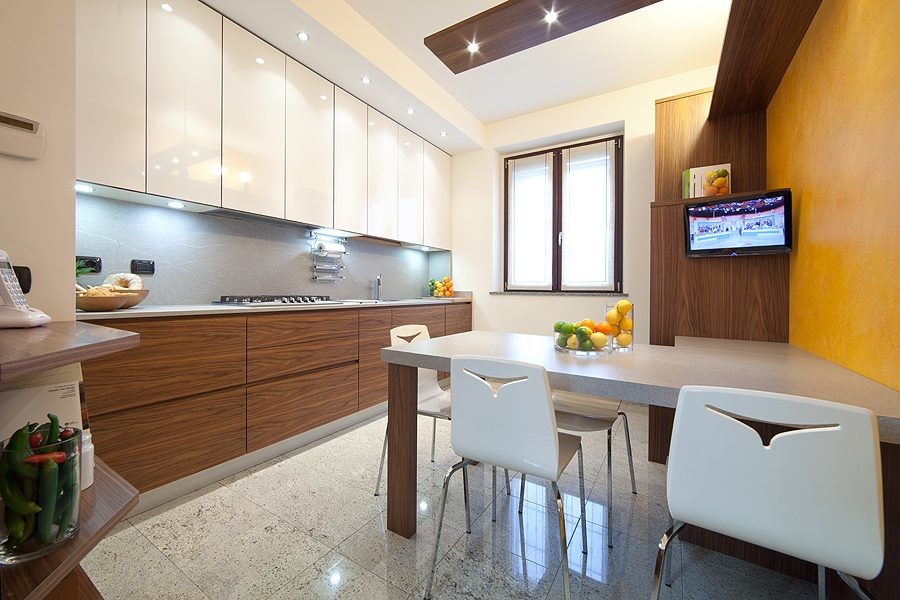 This is an example of a large modern single-wall separate kitchen in Milan with a double-bowl sink, flat-panel cabinets, dark wood cabinets, solid surface benchtops, grey splashback, stainless steel appliances and porcelain floors.