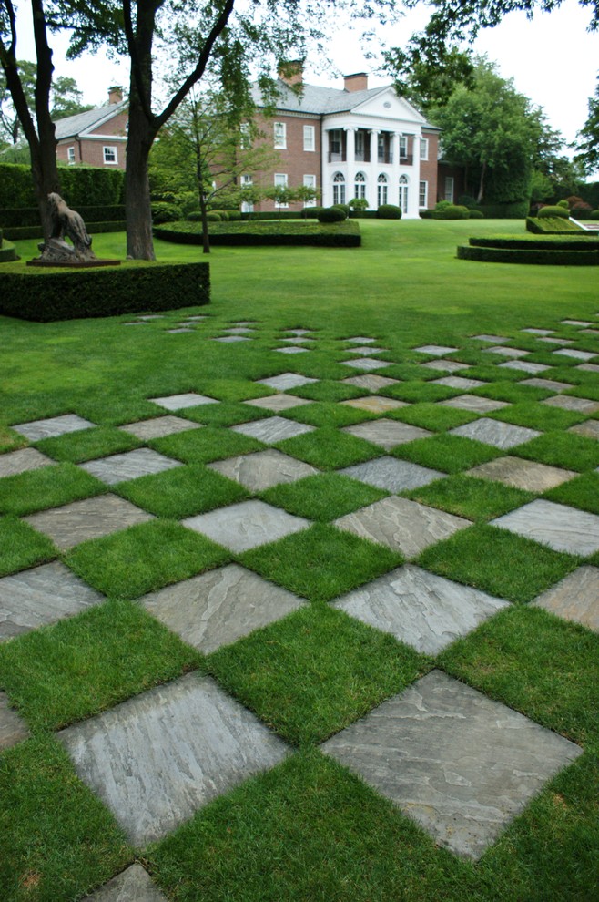 This is an example of an expansive traditional backyard formal garden in Chicago with natural stone pavers.