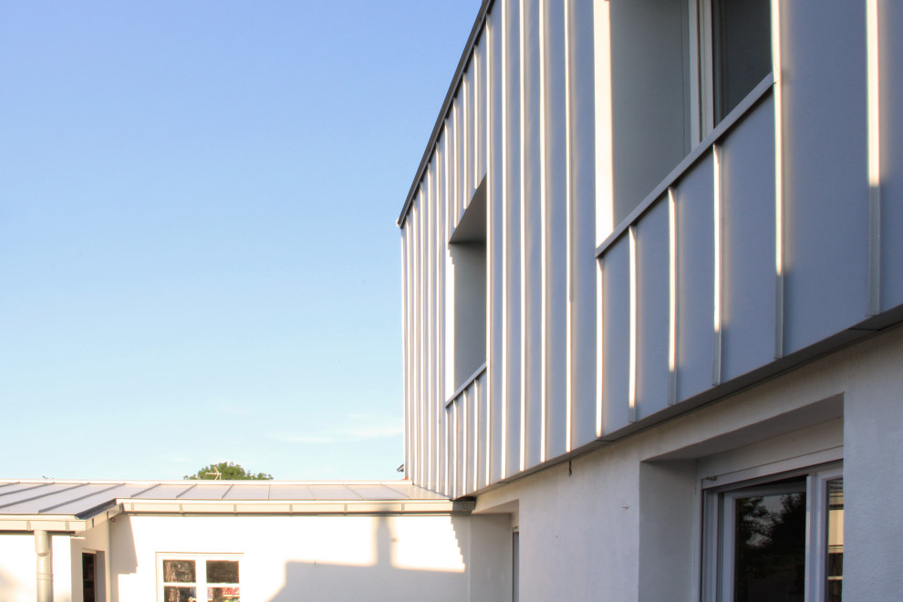 Diseño de fachada de casa pareada gris y gris actual de tamaño medio de tres plantas con revestimiento de metal, tejado a dos aguas, tejado de metal y panel y listón
