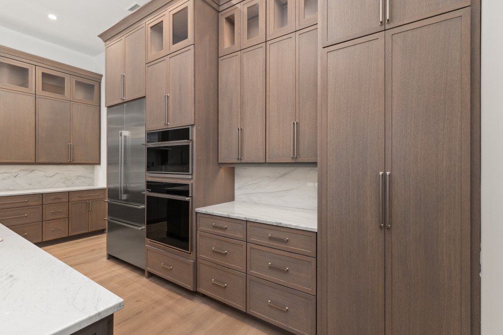 Eat-in kitchen - large transitional galley light wood floor and brown floor eat-in kitchen idea in Tampa with a double-bowl sink, shaker cabinets, dark wood cabinets, quartz countertops, gray backsplash, stone slab backsplash, stainless steel appliances, an island and gray countertops