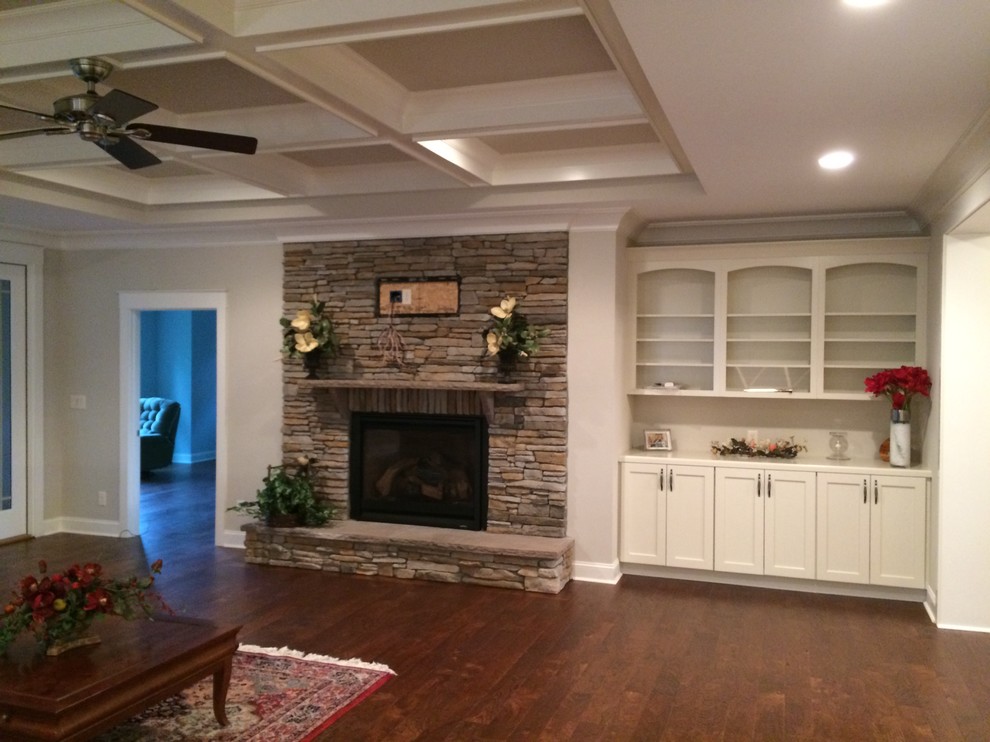 This is an example of a large traditional loft-style family room in Other with beige walls, medium hardwood floors, a standard fireplace, a stone fireplace surround, a wall-mounted tv and brown floor.