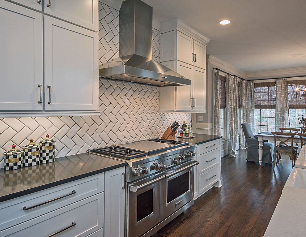 Large transitional l-shaped medium tone wood floor and brown floor open concept kitchen photo in Atlanta with a farmhouse sink, shaker cabinets, white cabinets, quartzite countertops, white backsplash, subway tile backsplash, stainless steel appliances and an island
