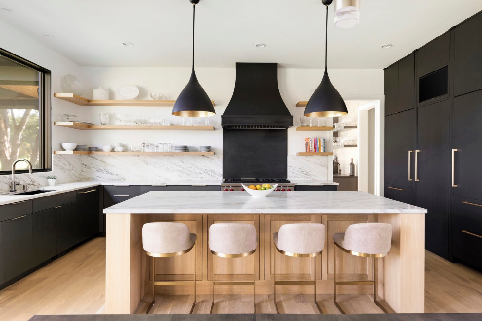 This is an example of a large contemporary l-shaped kitchen/diner in Minneapolis with a built-in sink, flat-panel cabinets, black cabinets, marble worktops, white splashback, marble splashback, stainless steel appliances, medium hardwood flooring, an island, beige floors and white worktops.