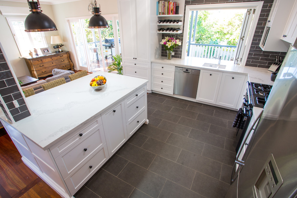 Inspiration for a large traditional l-shaped open plan kitchen in Brisbane with an undermount sink, shaker cabinets, white cabinets, quartz benchtops, grey splashback, subway tile splashback, black appliances, ceramic floors, with island and grey floor.