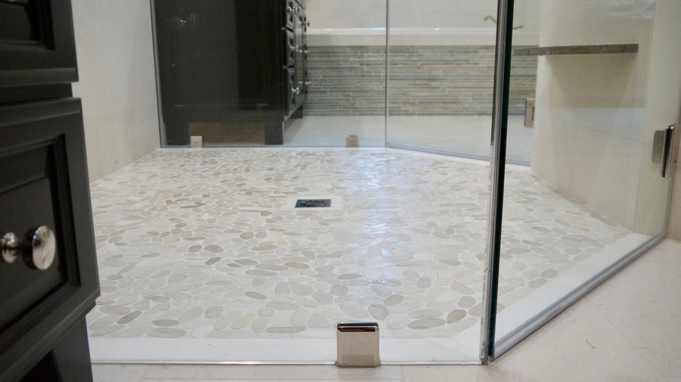 Photo of a mid-sized transitional master bathroom in Los Angeles with a curbless shower, limestone, beige walls, pebble tile floors and a hinged shower door.