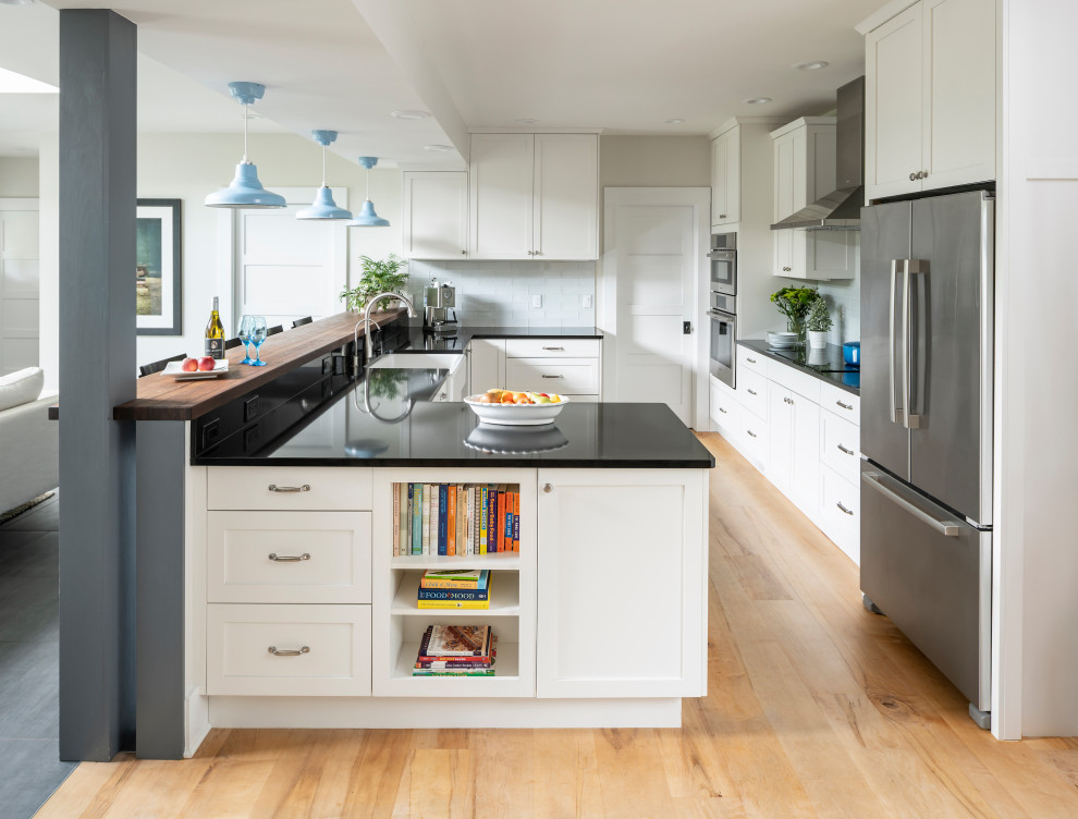 Inredning av ett klassiskt mellanstort grå grått kök, med en rustik diskho, skåp i shakerstil, vita skåp, bänkskiva i kvarts, vitt stänkskydd, stänkskydd i keramik, rostfria vitvaror, ljust trägolv, en halv köksö och beiget golv