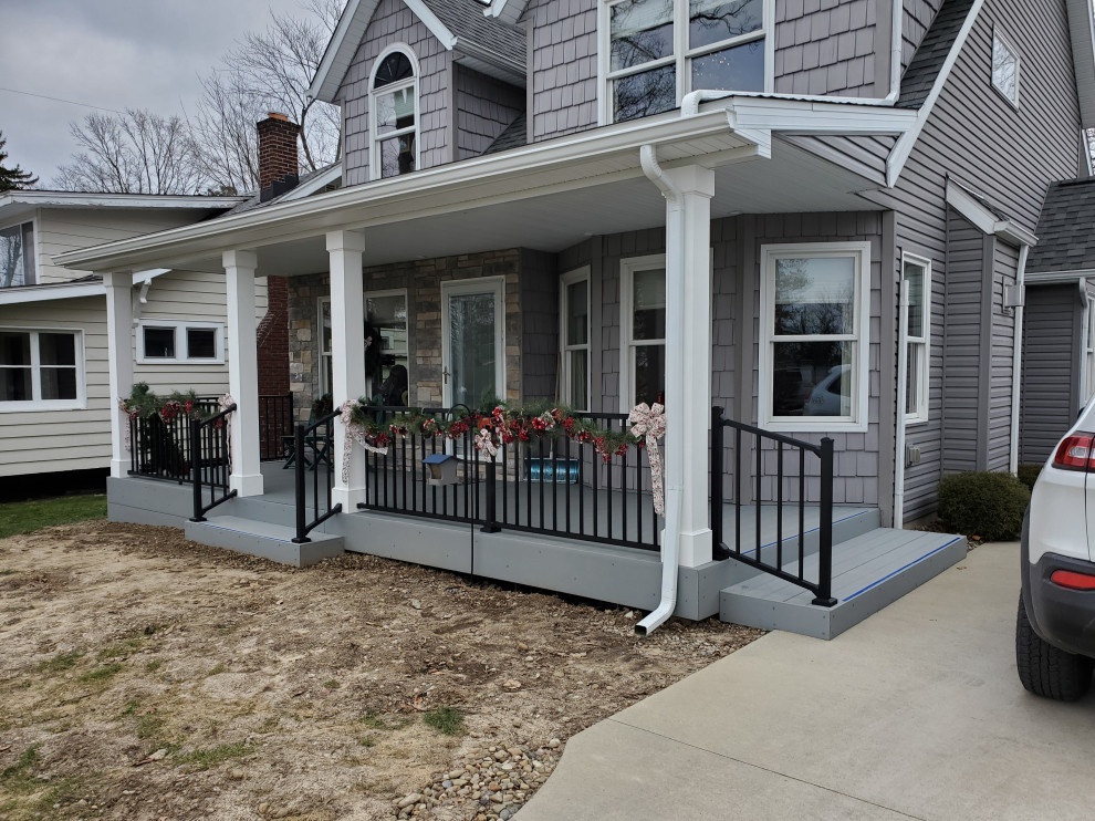 This is an example of a mid-sized arts and crafts front yard verandah in Cleveland with with skirting, decking, a roof extension and metal railing.