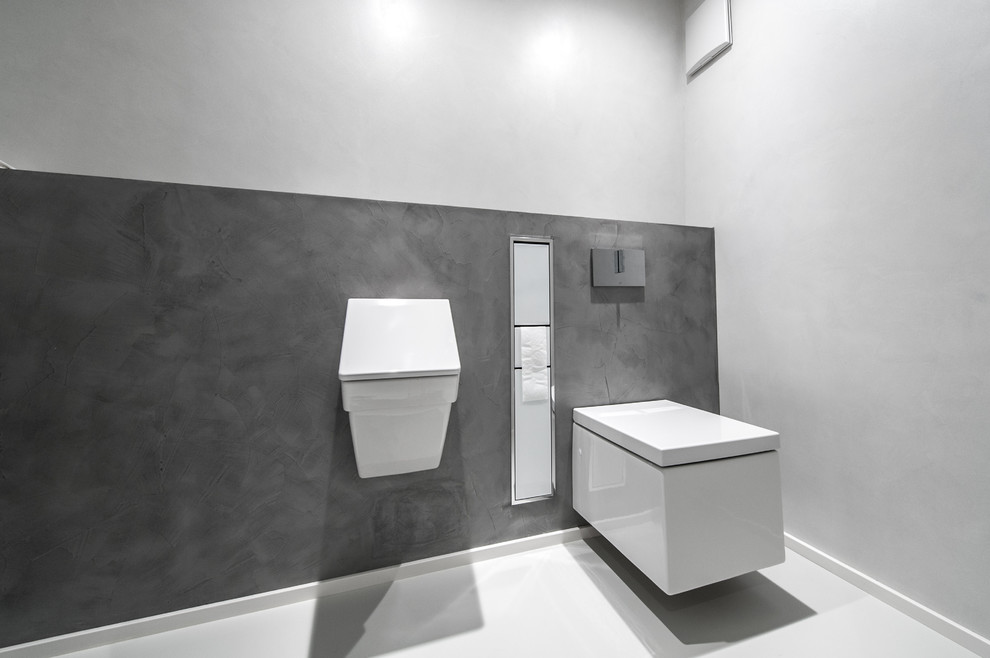 This is an example of a small modern powder room in Stuttgart with a wall-mount toilet, white walls, vinyl floors and white floor.