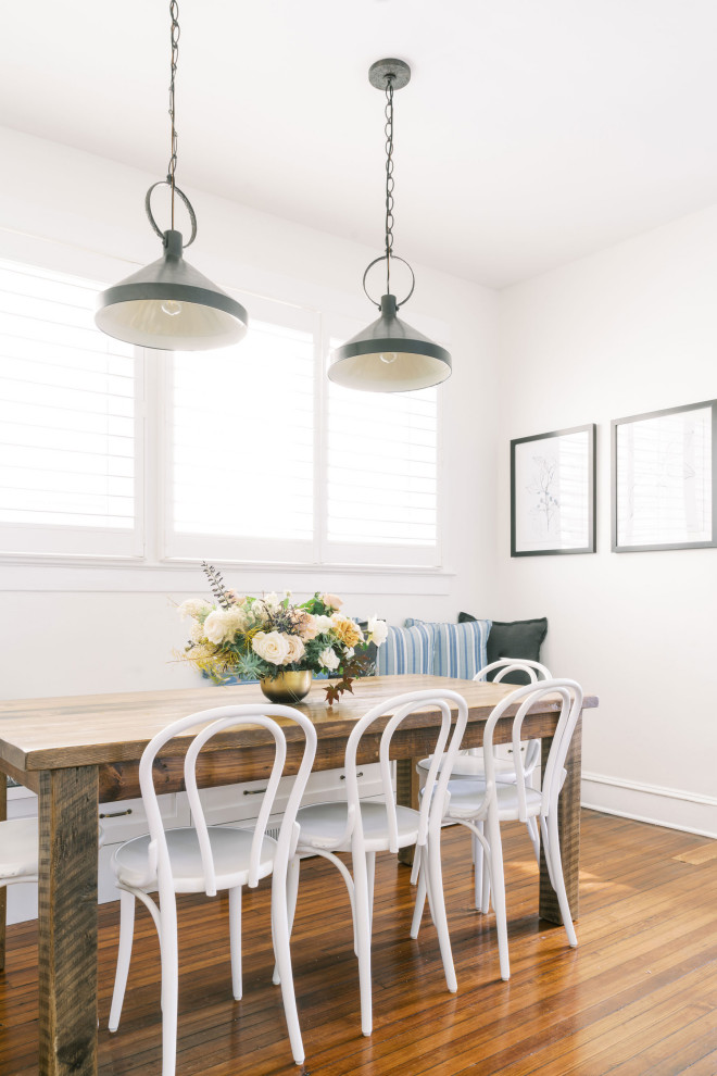 Cette photo montre une salle à manger ouverte sur la cuisine chic avec un mur blanc, un sol en bois brun et un sol marron.