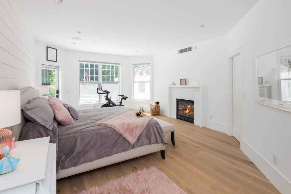 Mittelgroßes Landhausstil Schlafzimmer mit gelber Wandfarbe, hellem Holzboden, Kaminumrandung aus Holzdielen und beigem Boden in Vancouver