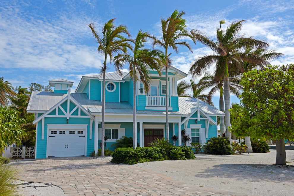 Large beach style two-storey blue house exterior in Orlando with a gable roof, a metal roof and mixed siding.