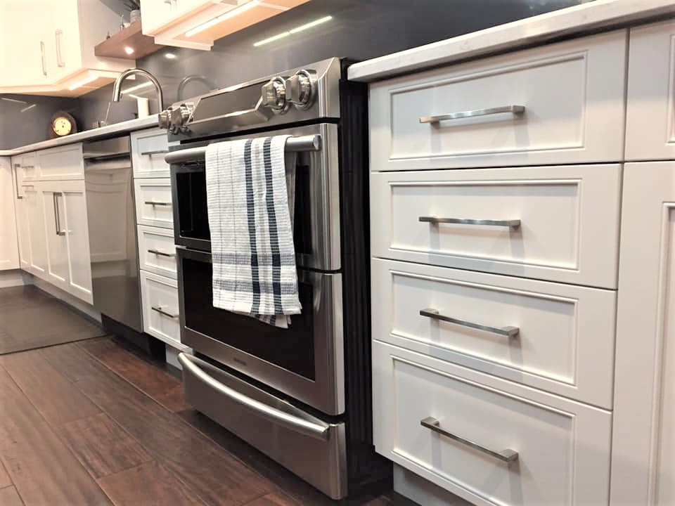 Example of a mid-sized transitional l-shaped dark wood floor and brown floor eat-in kitchen design in Ottawa with an undermount sink, recessed-panel cabinets, white cabinets, quartz countertops, blue backsplash, quartz backsplash, stainless steel appliances, an island and white countertops