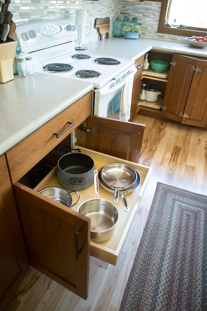 Eat-in kitchen - large transitional l-shaped light wood floor eat-in kitchen idea in Cedar Rapids with a double-bowl sink, recessed-panel cabinets, medium tone wood cabinets, laminate countertops, multicolored backsplash, mosaic tile backsplash, white appliances and an island