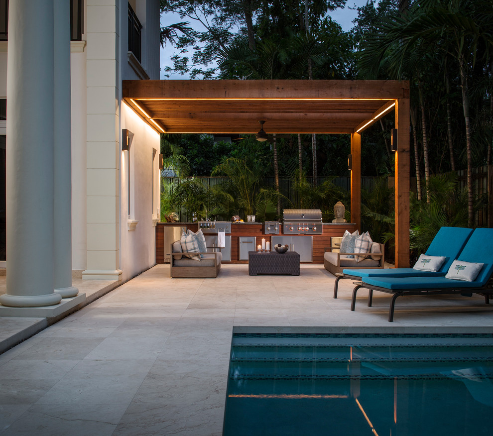Mid-sized island style backyard stone patio kitchen photo in Miami with a pergola