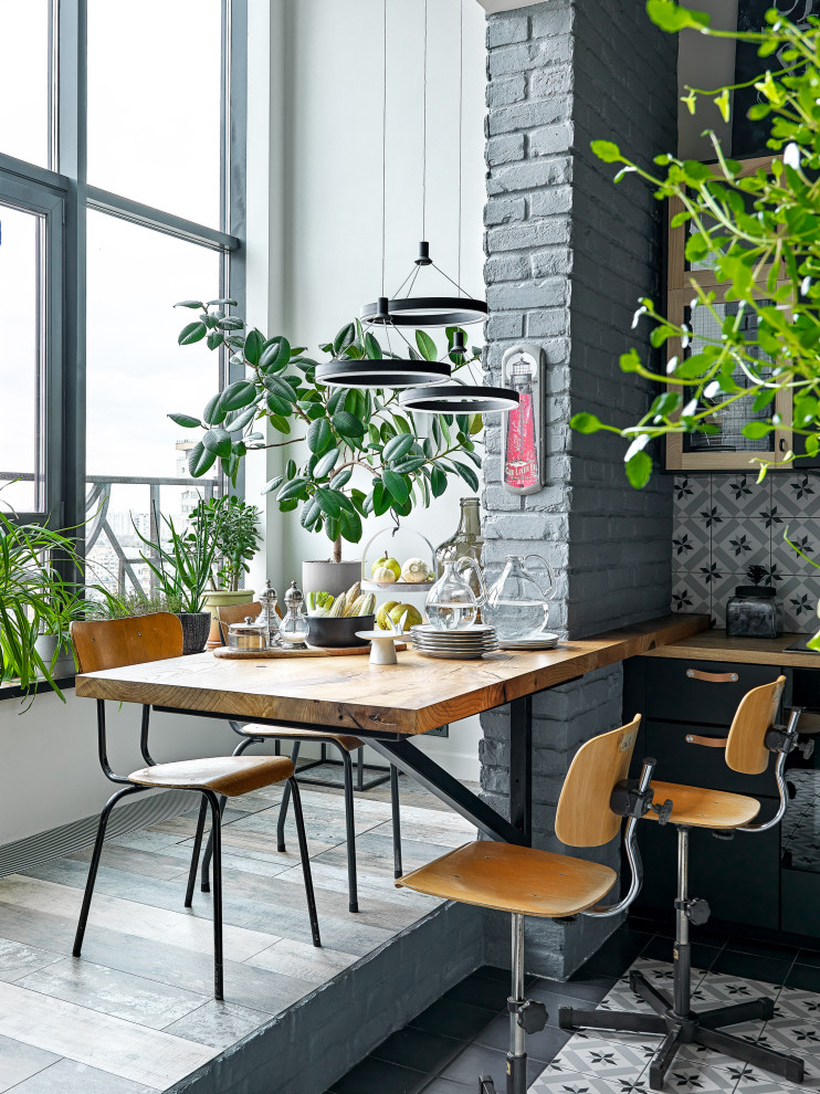 Photo of a mid-sized industrial l-shaped eat-in kitchen in Moscow with an undermount sink, flat-panel cabinets, black cabinets, wood benchtops, multi-coloured splashback, ceramic splashback, black appliances, ceramic floors, no island, blue floor and brown benchtop.