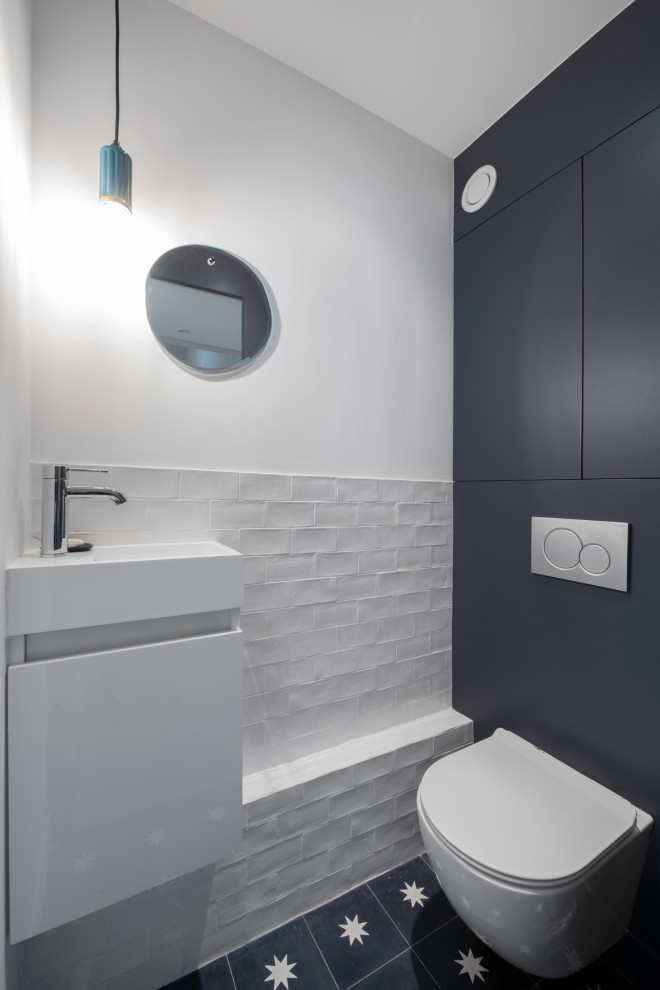 Пример оригинального дизайна: туалет среднего размера в стиле модернизм с фасадами с декоративным кантом, черными фасадами, инсталляцией, белой плиткой, терракотовой плиткой, белыми стенами, полом из цементной плитки, подвесной раковиной, столешницей из искусственного камня, черным полом, белой столешницей и встроенной тумбой