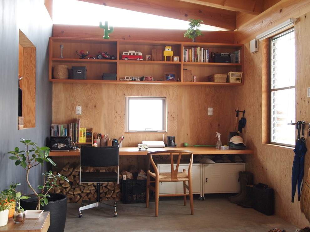 This is an example of a small asian home office in Other with concrete floors, brown walls and a built-in desk.
