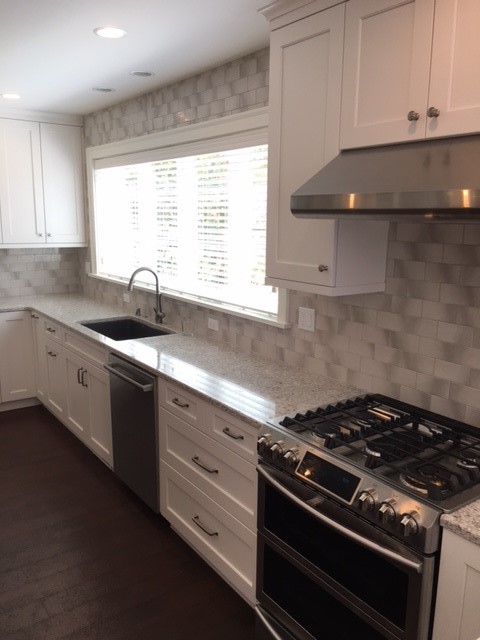 Large transitional open plan kitchen in Seattle with an undermount sink, shaker cabinets, white cabinets, quartz benchtops, multi-coloured splashback, glass tile splashback, stainless steel appliances, dark hardwood floors, with island and brown floor.