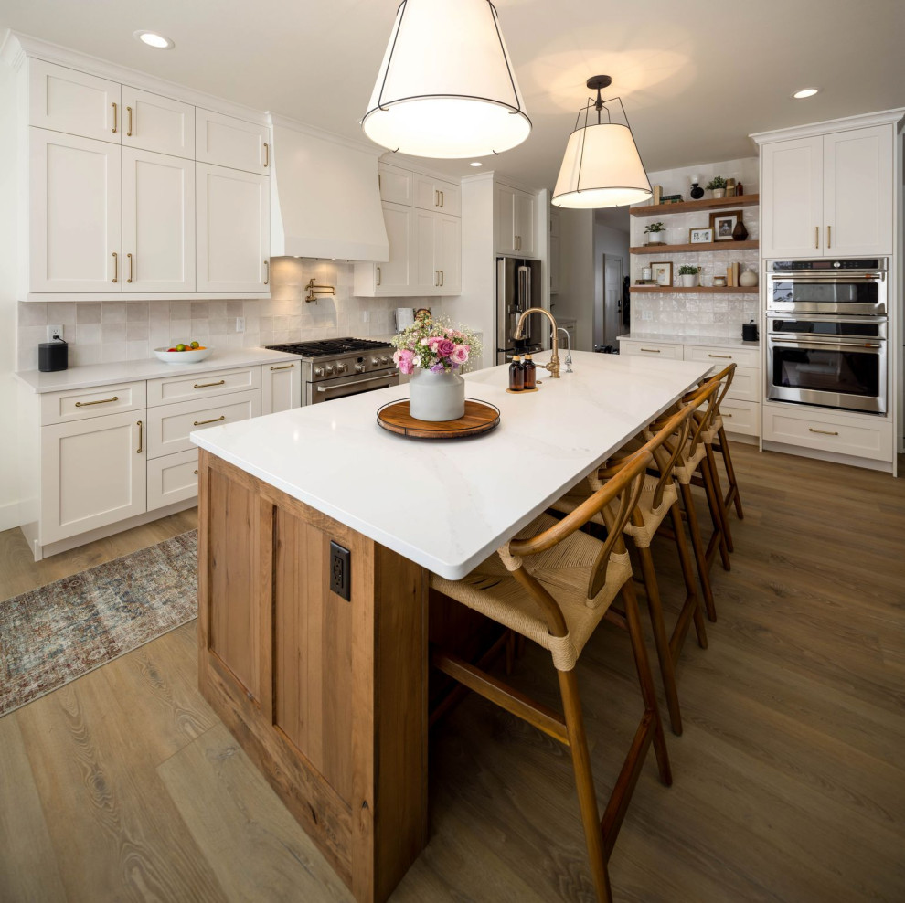 Example of a transitional l-shaped eat-in kitchen design with shaker cabinets, white cabinets and an island