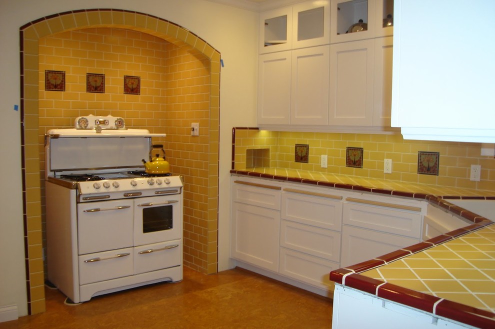 Inspiration for a mid-sized arts and crafts u-shaped open plan kitchen in Los Angeles with an undermount sink, recessed-panel cabinets, white cabinets, tile benchtops, yellow splashback, ceramic splashback, white appliances, vinyl floors, no island, beige floor and yellow benchtop.