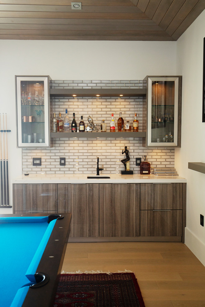 Foto di un grande angolo bar con lavandino minimalista con lavello da incasso, ante lisce, ante grigie, top in quarzite, paraspruzzi a specchio, parquet chiaro, pavimento beige e top bianco