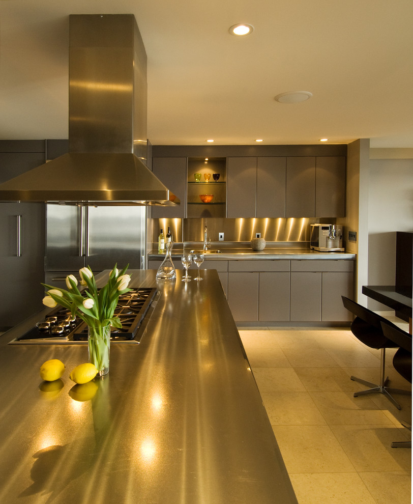 Large contemporary u-shaped open plan kitchen in Hawaii with flat-panel cabinets, grey cabinets, stainless steel benchtops, stainless steel appliances, with island, beige floor, an integrated sink, metallic splashback, metal splashback, ceramic floors and multi-coloured benchtop.