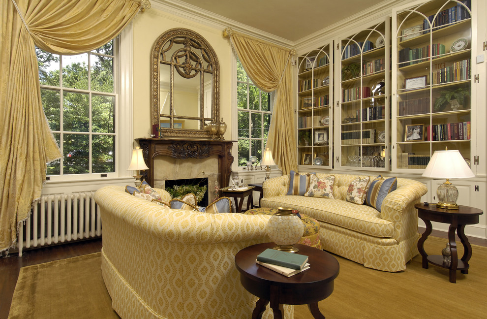 Traditional living room in DC Metro with a library, beige walls and a standard fireplace.