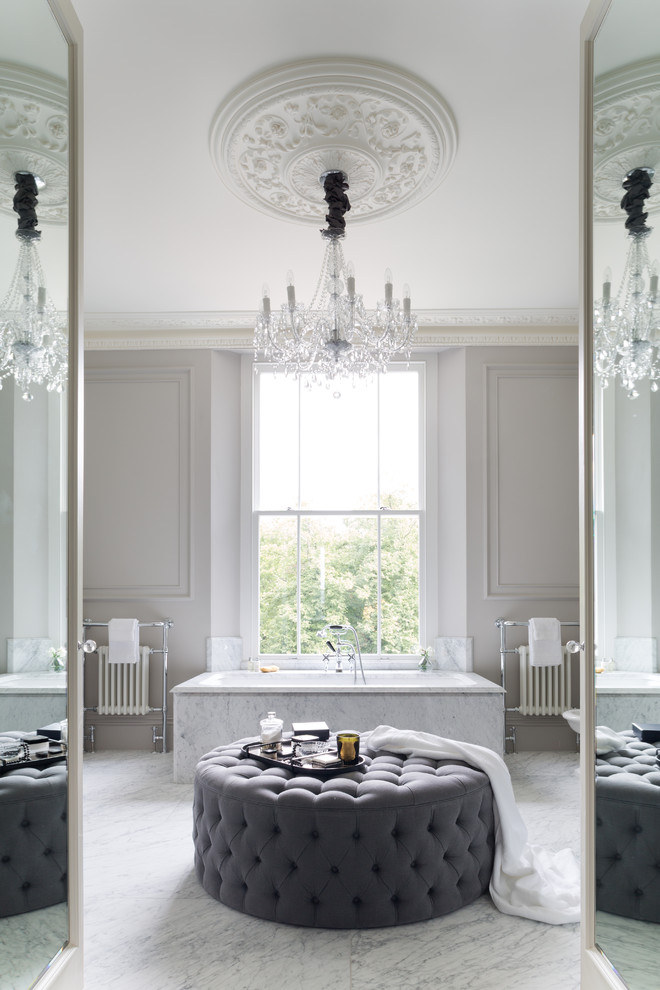 Design ideas for a transitional master bathroom in London with a drop-in tub and marble floors.