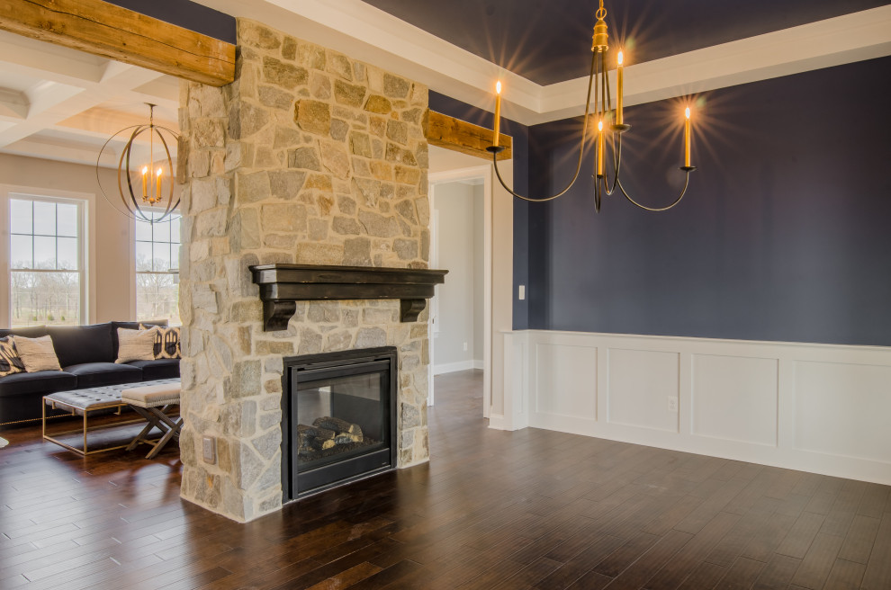 Dining room in Baltimore with blue walls, dark hardwood floors, a two-sided fireplace, a stone fireplace surround, brown floor, recessed and decorative wall panelling.