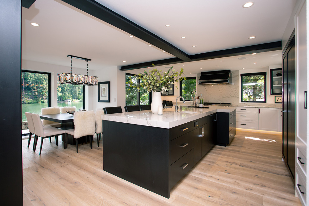 Large modern u-shaped eat-in kitchen in Portland with a drop-in sink, black cabinets, panelled appliances, medium hardwood floors, with island, brown floor and grey benchtop.