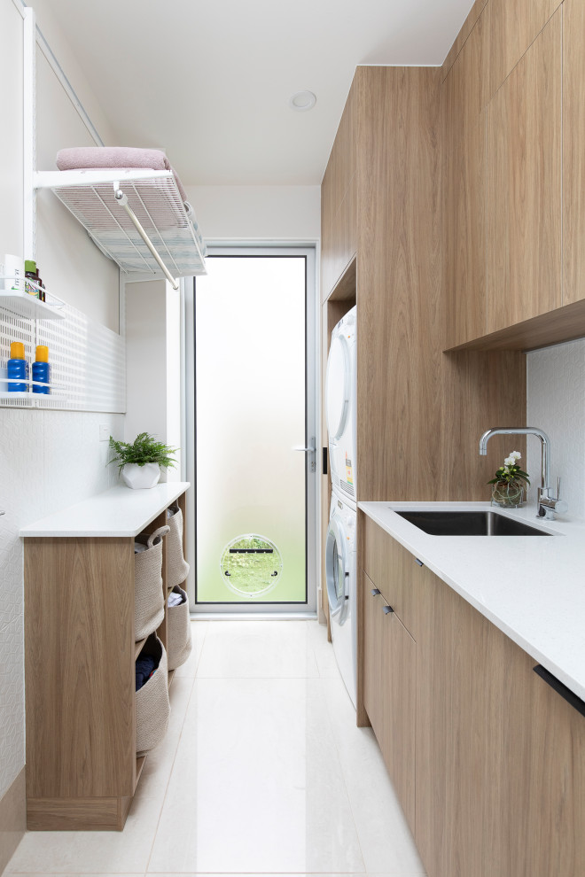 Zweizeilige, Kleine Moderne Waschküche mit Unterbauwaschbecken, hellen Holzschränken, Mineralwerkstoff-Arbeitsplatte, Rückwand aus Porzellanfliesen, weißer Wandfarbe und weißer Arbeitsplatte in Brisbane