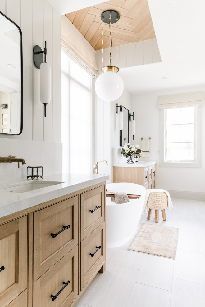 Inspiration for a classic bathroom in Salt Lake City with beaded cabinets, light wood cabinets, a freestanding bath, white walls, a submerged sink, white floors, white worktops, double sinks and a freestanding vanity unit.