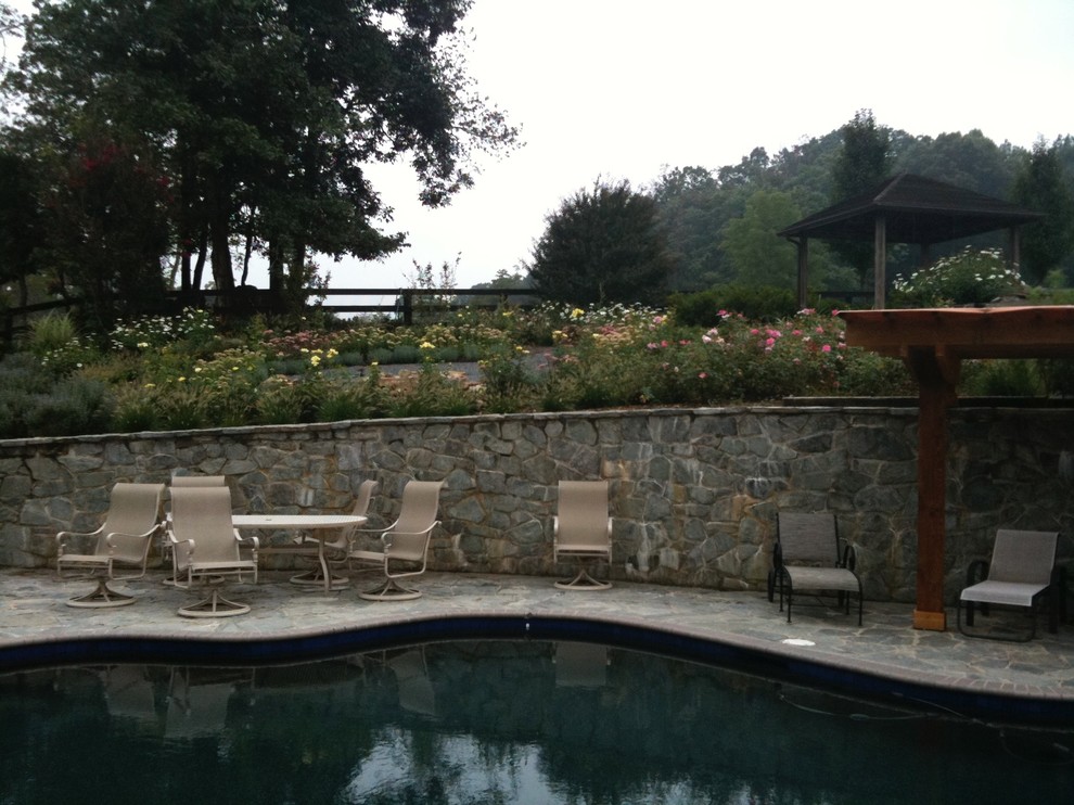 This is an example of a large rustic partial sun backyard stone formal garden for summer.