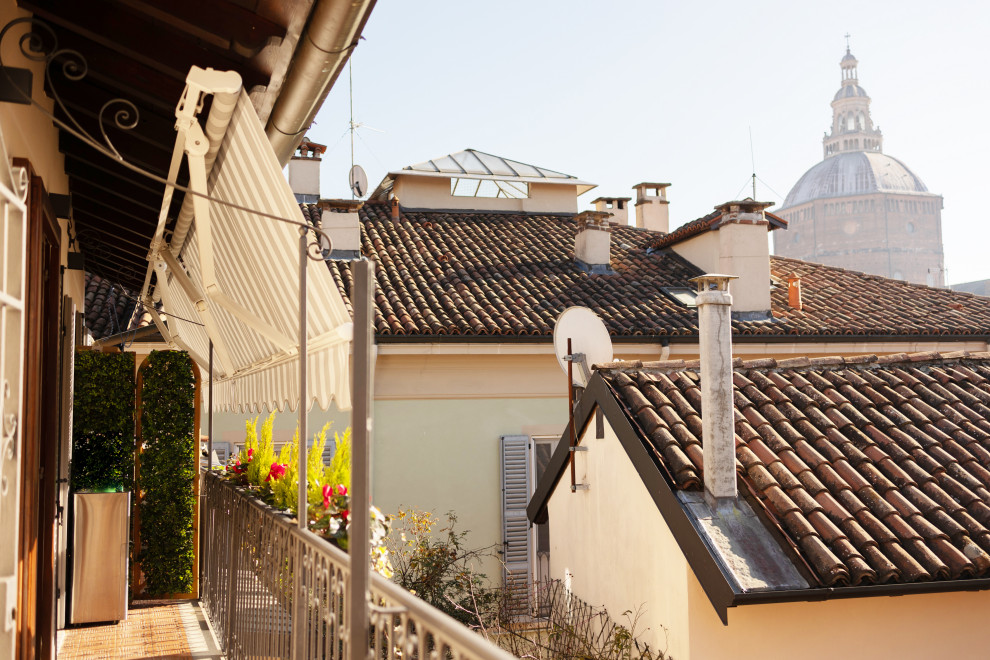 Cette image montre un petit balcon traditionnel d'appartement avec une extension de toiture et un garde-corps en métal.
