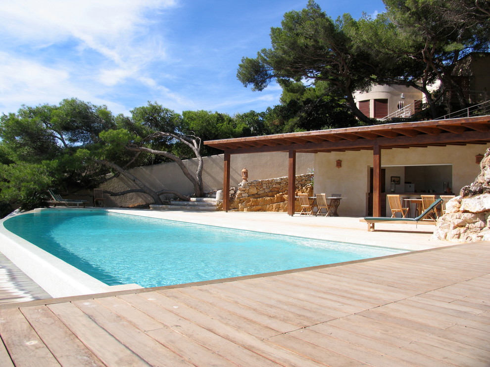 Design ideas for a large mediterranean custom-shaped pool in Marseille with a pool house and decking.