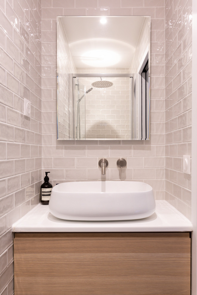 Inspiration för mellanstora moderna vitt badrum med dusch, med skåp i ljust trä, en dusch i en alkov, en toalettstol med separat cisternkåpa, vit kakel, keramikplattor, blå väggar, ljust trägolv, ett nedsänkt handfat, träbänkskiva, brunt golv och dusch med gångjärnsdörr