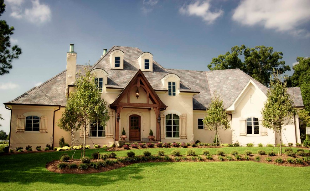 This is an example of a large traditional two-storey stucco beige house exterior in Austin with a hip roof and a shingle roof.