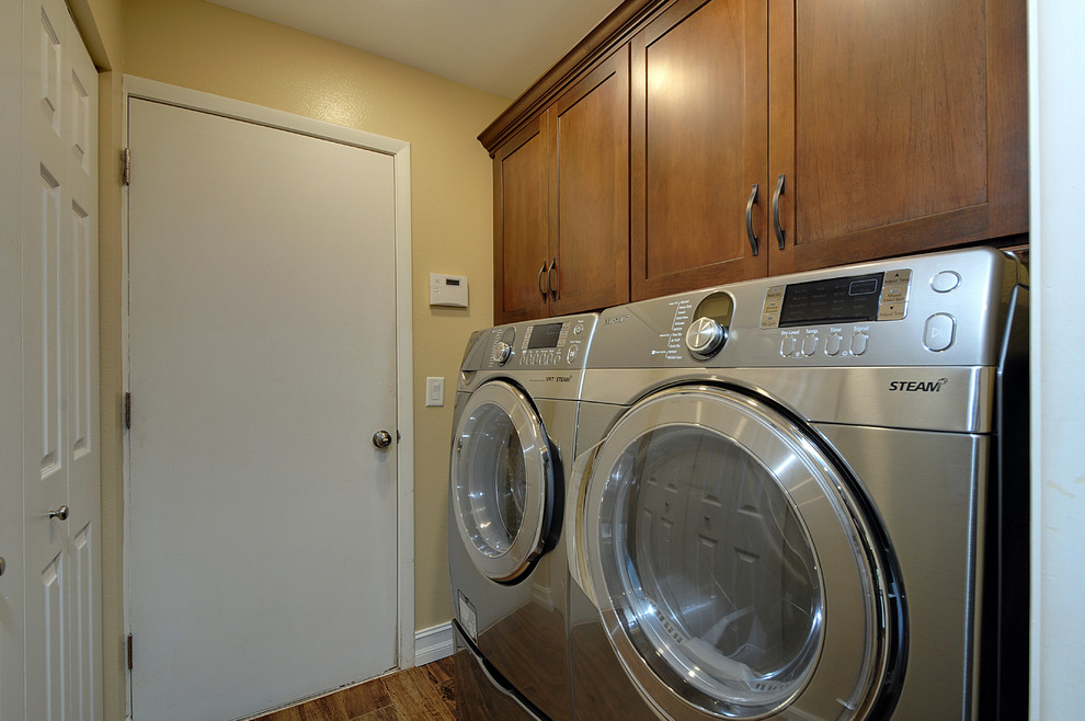 This is an example of a mid-sized tropical u-shaped laundry room in Tampa with an undermount sink, shaker cabinets, medium wood cabinets, laminate benchtops, beige walls, porcelain floors and a side-by-side washer and dryer.