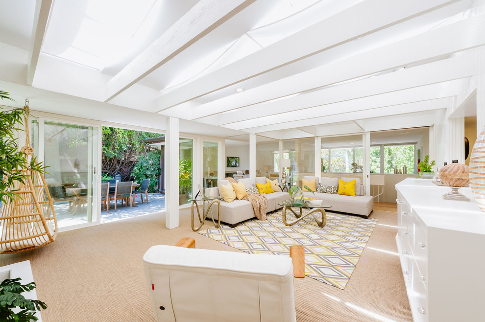 This is an example of a large midcentury sunroom in Los Angeles with carpet, a skylight and beige floor.