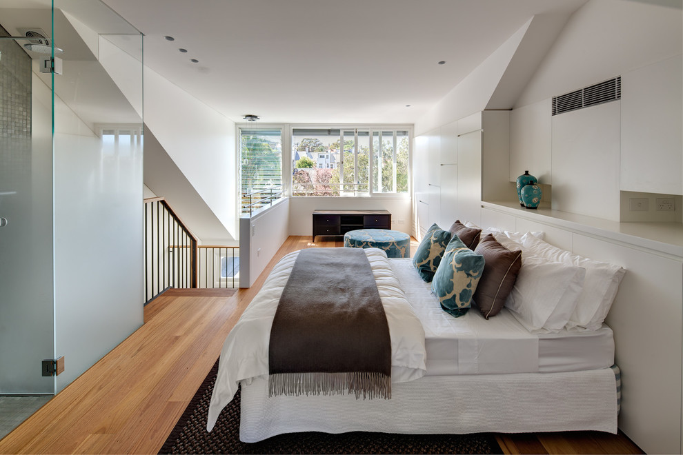 Mid-sized contemporary loft-style bedroom in Sydney with white walls, no fireplace and medium hardwood floors.