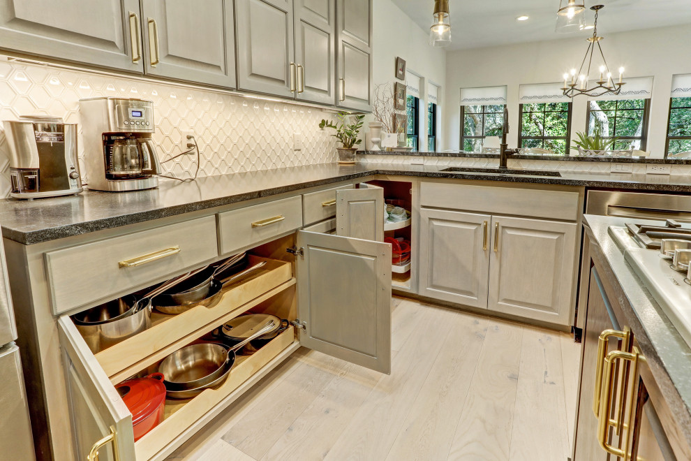 Inspiration for a mid-sized transitional u-shaped light wood floor and beige floor enclosed kitchen remodel in Austin with a single-bowl sink, recessed-panel cabinets, gray cabinets, quartzite countertops, white backsplash, porcelain backsplash, stainless steel appliances, an island and green countertops