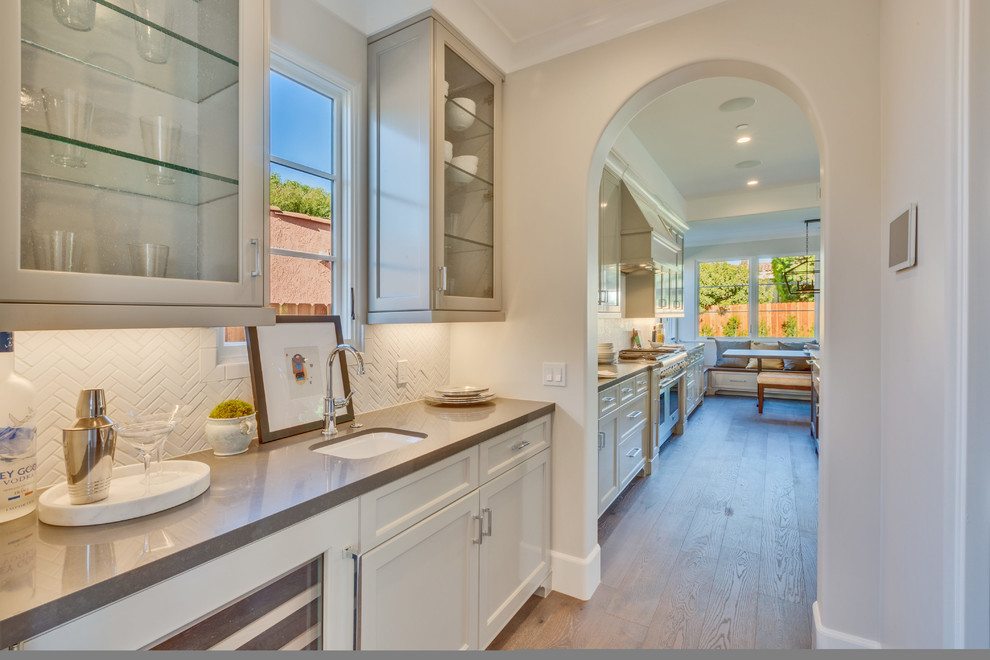 This is an example of a transitional single-wall kitchen pantry in Los Angeles with an undermount sink, recessed-panel cabinets, beige cabinets, white splashback, light hardwood floors and beige floor.