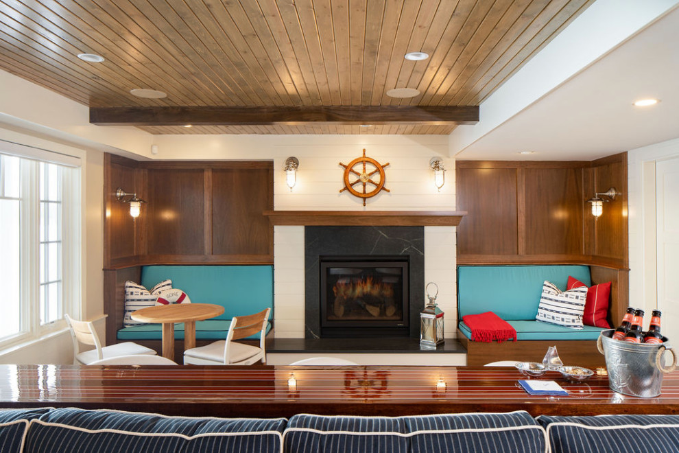 Design ideas for a mid-sized beach style walk-out basement in Minneapolis with a home bar, white walls, light hardwood floors, a standard fireplace, a stone fireplace surround, brown floor, exposed beam and planked wall panelling.