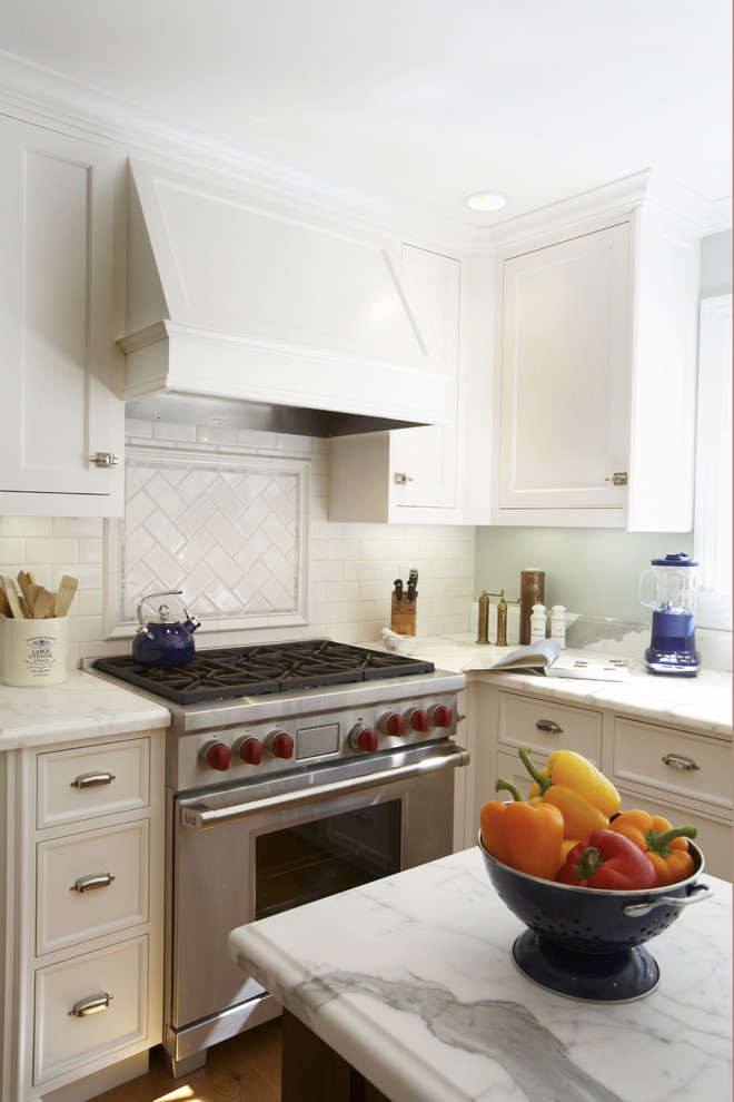Design ideas for a mid-sized traditional l-shaped eat-in kitchen in San Francisco with subway tile splashback, white cabinets, white splashback, stainless steel appliances, a farmhouse sink, marble benchtops, medium hardwood floors, with island and shaker cabinets.