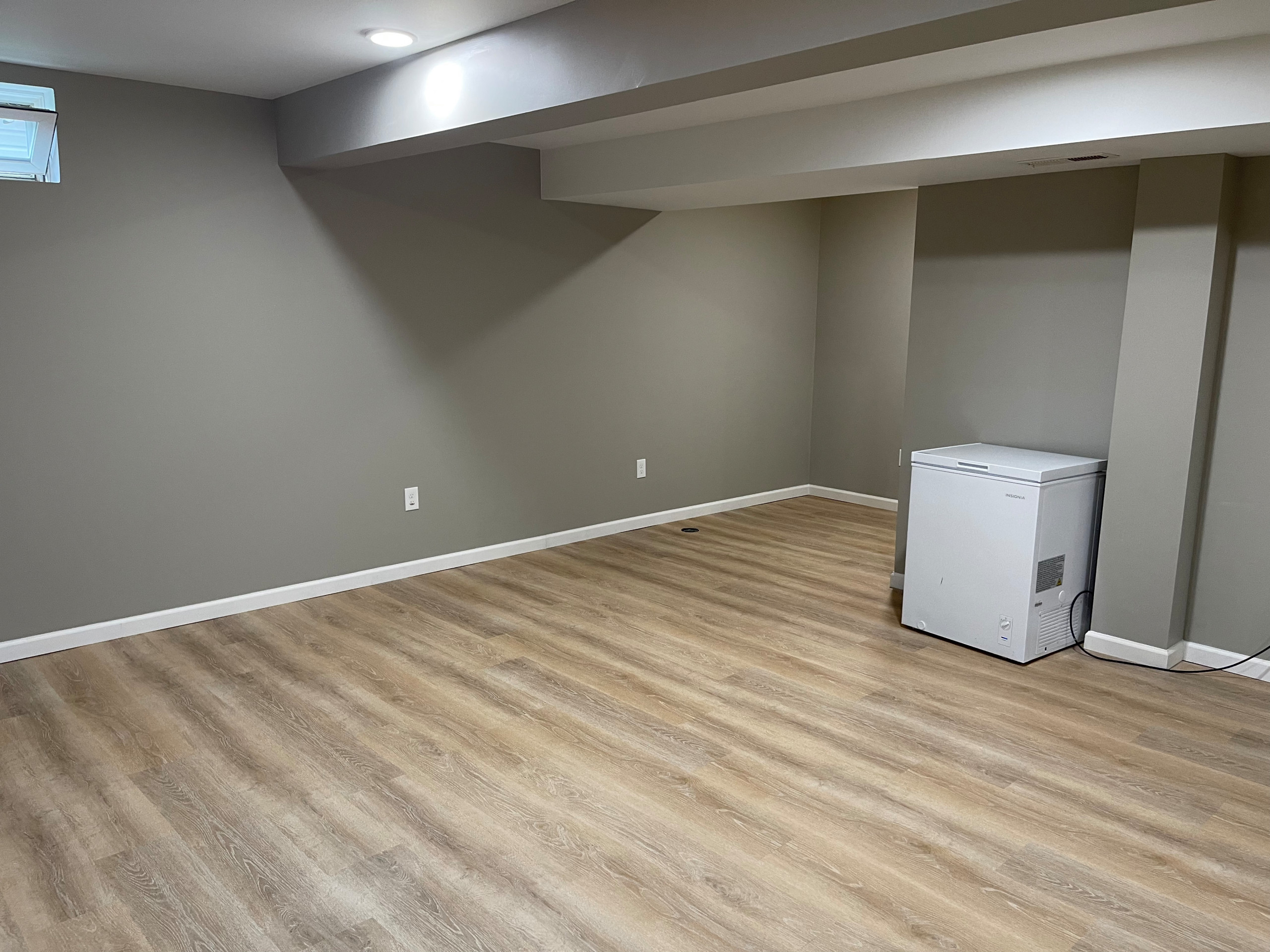 Basement - large modern underground vinyl floor and brown floor basement idea in Cleveland with gray walls and no fireplace
