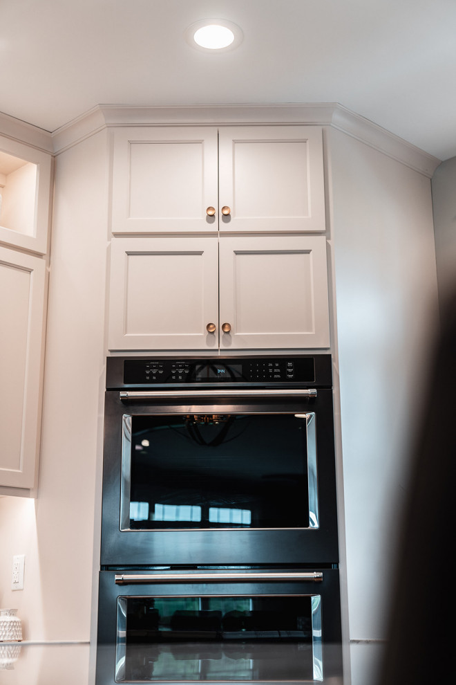 Example of a large transitional l-shaped medium tone wood floor and brown floor open concept kitchen design with an undermount sink, flat-panel cabinets, white cabinets, quartz countertops, multicolored backsplash, quartz backsplash, black appliances, an island and multicolored countertops