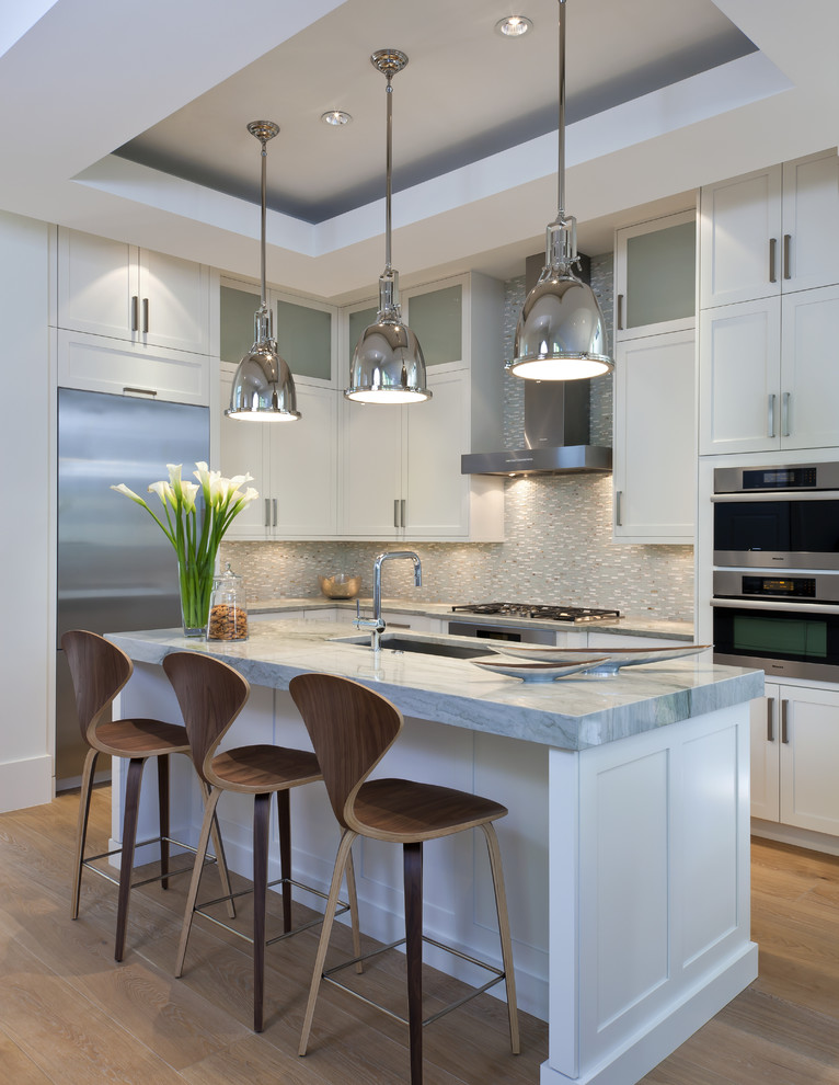 Design ideas for a mid-sized transitional l-shaped kitchen in Miami with an undermount sink, shaker cabinets, white cabinets, grey splashback, mosaic tile splashback, stainless steel appliances, medium hardwood floors and with island.